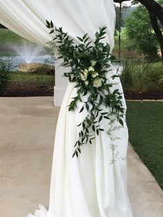 a white wedding dress with flowers and greenery on the front, draped over an outdoor area