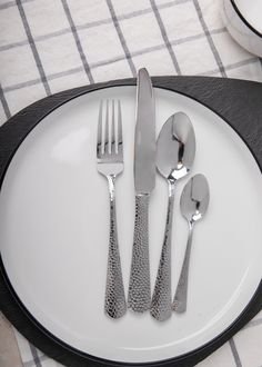 a white plate topped with silverware on top of a black and white table cloth