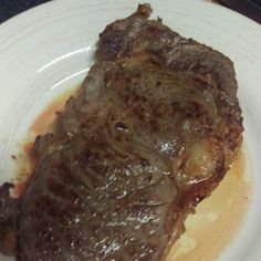 a piece of steak sitting on top of a white plate covered in gravy