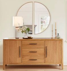 a wooden sideboard with a mirror and vase on top