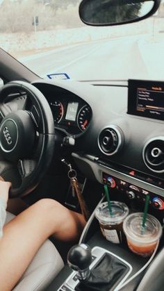 a woman sitting in the driver's seat of a car with her hand on the steering wheel