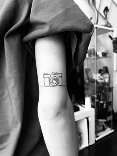 a camera tattoo on the left arm and wrist is shown in this black and white photo