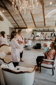 a group of women standing around in a room with chandeliers hanging from the ceiling