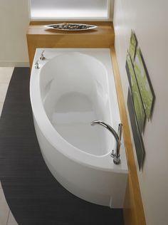 an oval shaped bathtub in the corner of a bathroom with a window above it