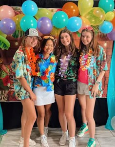 three girls standing in front of a backdrop with balloons