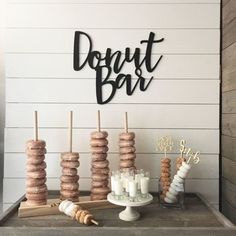 an assortment of donuts are displayed on a table in front of a sign that says donut bar