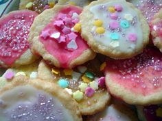 there are many cookies with sprinkles on the top one is pink and white