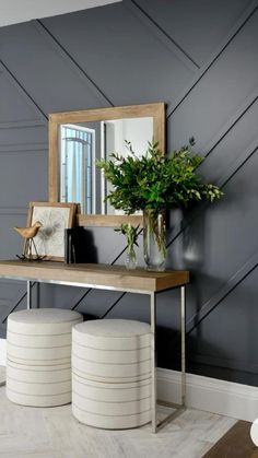 a table with two stools and a mirror on the wall above it in a room