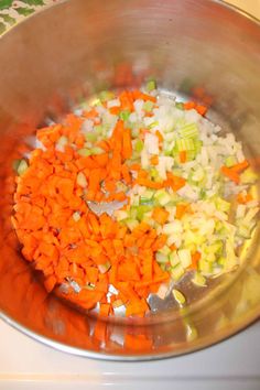 chopped vegetables in a metal bowl on top of a stove burner, ready to be cooked