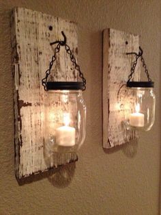 two mason jars are hanging on the wall with candles in them and one candle is lit