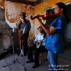 three people are playing instruments in an old room