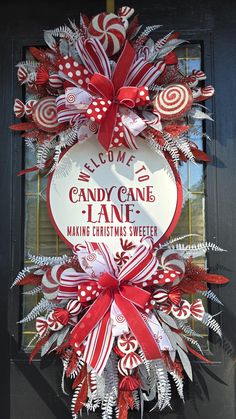 a red and white christmas wreath with candy canes hanging on the front door,