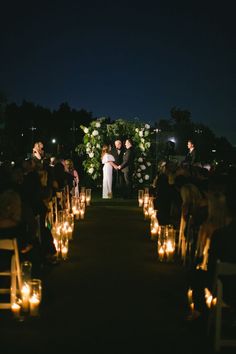 a bride and groom standing at the end of their wedding ceremony with candles in front of them