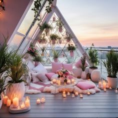 a room filled with lots of plants and candles on top of a wooden floor next to a window