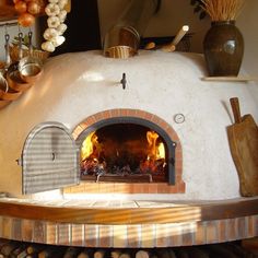 an outdoor pizza oven with lots of wood and fire in the center, surrounded by pots and pans