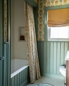 a bath room with a toilet and a tub next to a window in the wall