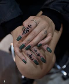 a woman with green nails and tattoos on her hands holding onto another person's hand