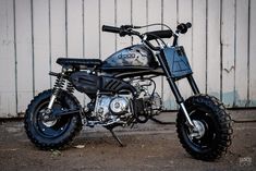 a motorcycle parked in front of a white building with graffiti on it's side