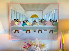 a painting of the last supper of jesus hangs above a table