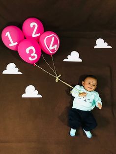 a baby is holding some balloons with numbers on them