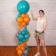 a woman standing next to a tall balloon column