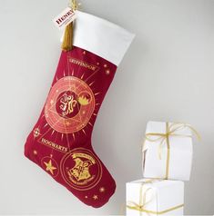 a red christmas stocking with hogwart's houses on it next to presents