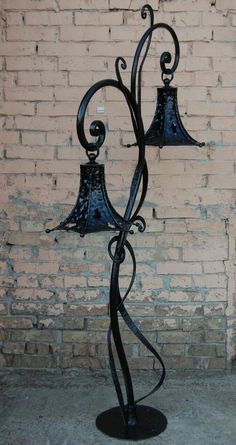 a metal lamp with two lamps on it in front of a brick wall