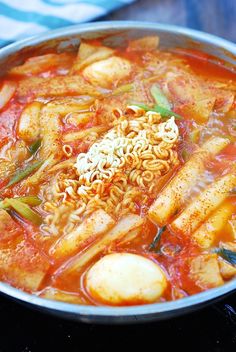 there is noodle soup in the pan on the stove top, but it's ready to be eaten