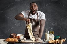 a man in an apron is making bread on a table with ingredients around him and his mouth wide open