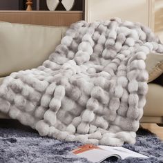 a fluffy blanket is on the floor next to a couch with pillows and a book