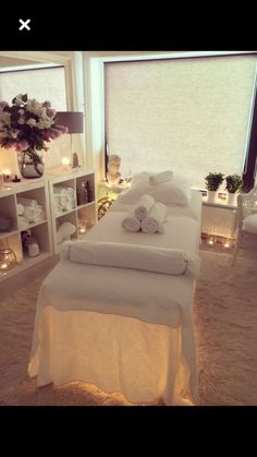 a white bed with towels on top of it in a room filled with candles and flowers