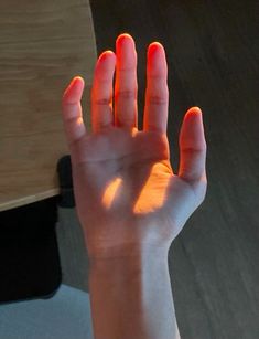 a person holding their hand up in the air with bright orange light shining on them