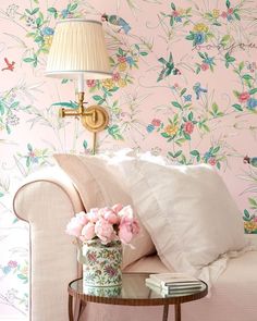 a living room with floral wallpaper and a white couch in front of a lamp