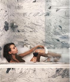 a woman sitting in a bathtub holding a glass of wine