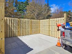 a man with a construction cone on his head standing in front of a wooden fence