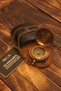 an antique pocket watch on a wooden table with a name tag and chain around it