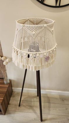 a white wicker lamp shade sitting on top of a wooden table next to a clock