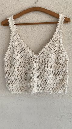 a white crop top hanging on a wooden hanger