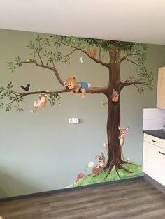 a child's room with a tree painted on the wall and stuffed animals hanging from it