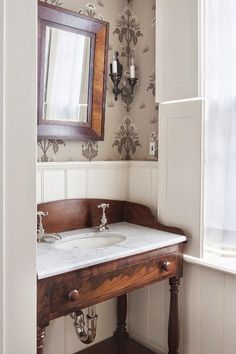 a bathroom sink sitting under a mirror next to a wooden cabinet and wall mounted faucet