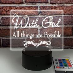 an illuminated sign with the words, with god all things are possible next to a remote control