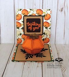 an orange origami card with the words thinking of you on it, sitting on top of a wooden table