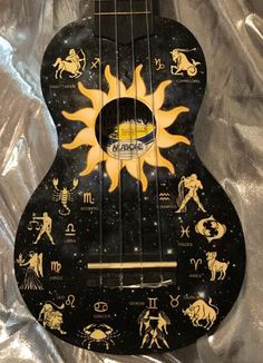 a black and yellow guitar with zodiac signs on it