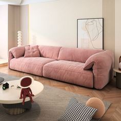 a living room with a pink couch and coffee table in the middle, on top of a wooden floor