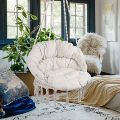 a white chair sitting on top of a rug next to a window filled with plants