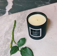 a candle sitting on top of a table next to a green leafy plant and a marble slab