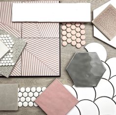 some tiles are laying on the floor and one is pink, grey, white and black