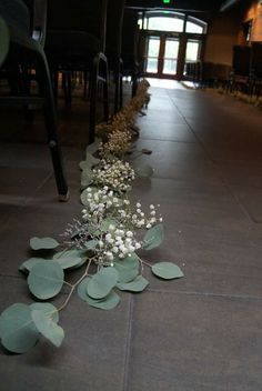 a long row of green leaves and white flowers on the ground in front of a building