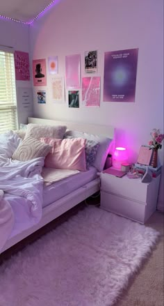 a white bed sitting in a bedroom next to a pink light on the nightstands