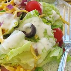 a salad with dressing and cheese is on a glass plate, ready to be eaten